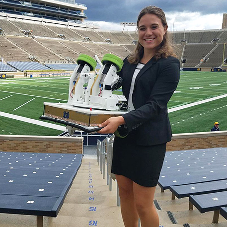 Engineering undergrad Cara Ravasio showing off a mechatronic football robot inside Notre Dame Stadium
