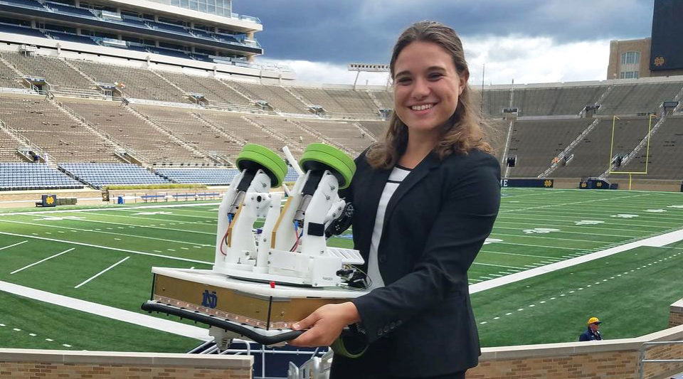 Engineering undergrad Cara Ravasio showing off a mechatronic football robot inside Notre Dame Stadium