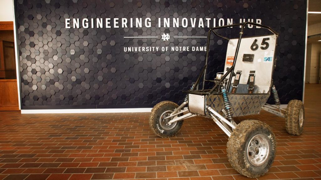 Notre Dame BajaSAE buggy in front of the Engineering Innovation Hub sign wall