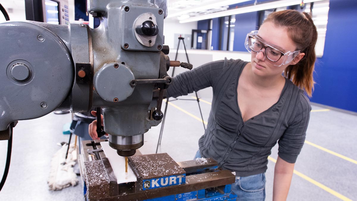 Female student operating a drill press in the Engineering Innovation Hub