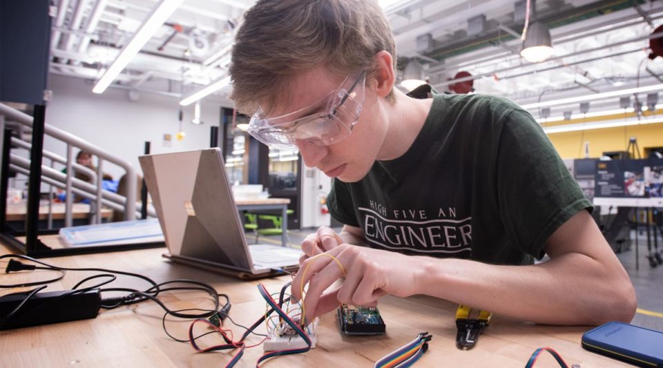 Male student wiring a device in the Engineering Innovation Hub