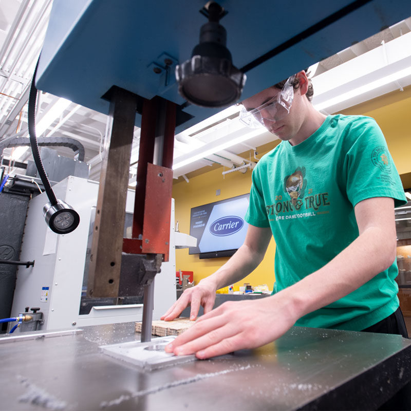 Male student using a band saw to cut material in the Engineering Innovation Hub